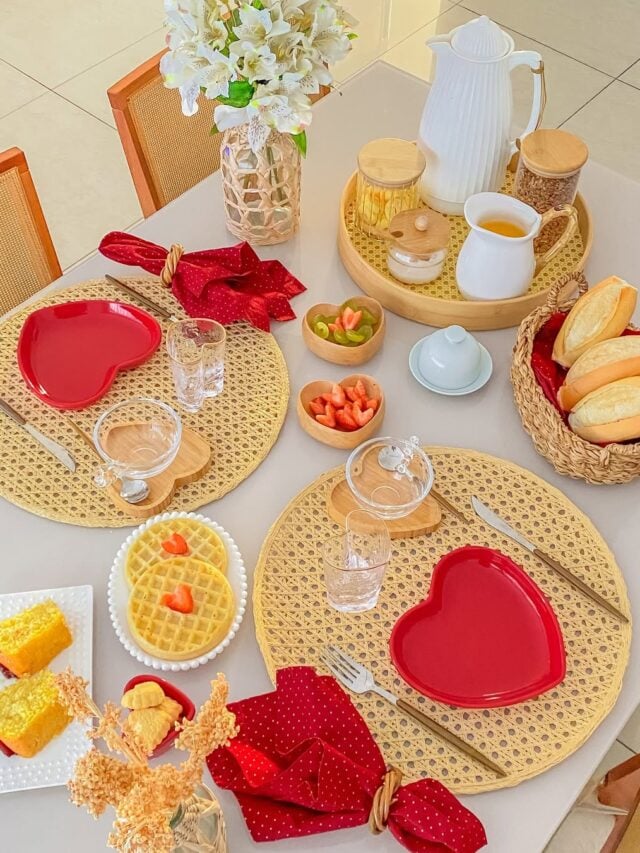 Mesa posta com sousplats de palhinha, pratos e copos em formato de coração e guardanapos vermelhos