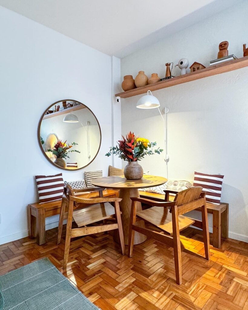 Sala de jantar com canto alemão, móveis de madeira e espelho redondo