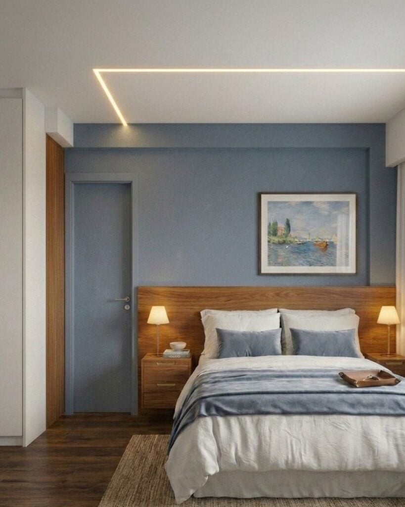 Quarto com parede azul atrás da cama, cabeceira de madeira e iluminação com led no teto
