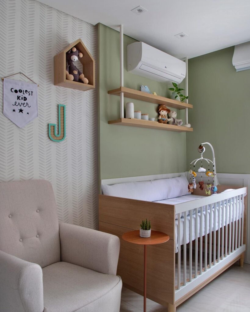 Quarto de bebê com parede verde-claro, prateleiras, berço e poltrona