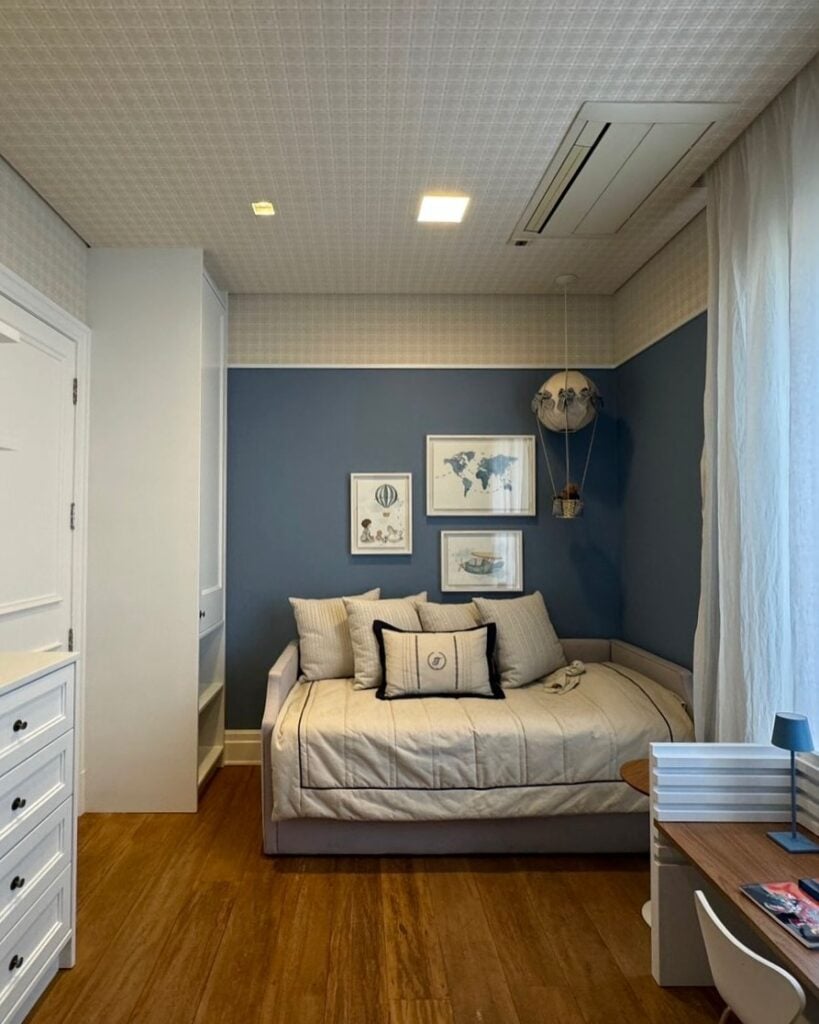 Quarto com móveis brancos e parede azul com quadros com mapas e balões
