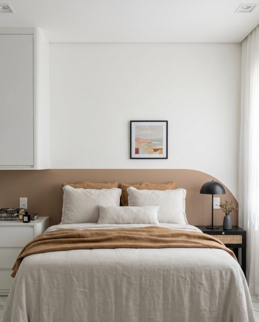 Quarto neutro com parede branca e parte pintada de nude, mesa de cabeceira preta com palhinha e luminária preta de metal