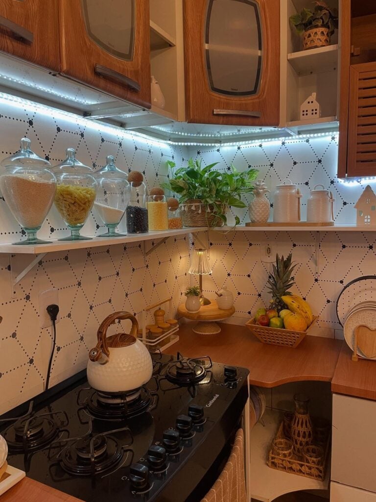 Cozinha com armários de madeira, iluminação em led e prateleiras abertas