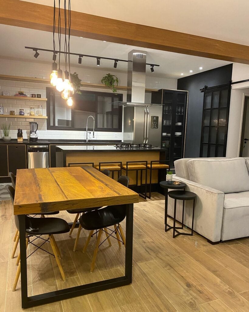 Cozinha e sala no estilo industrial com madeira aparente e metais pretos