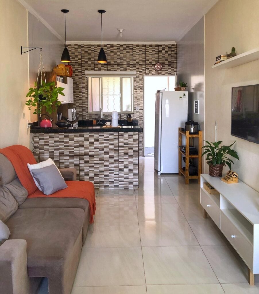 Cozinha e sala integradas com sofá cinza e revestimento em tons de cinza na parte da cozinha