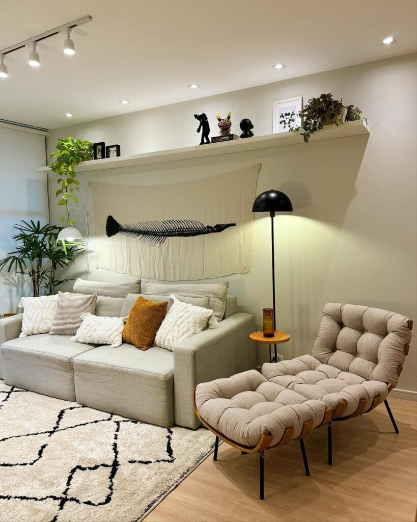 Sala com sofá de linhas retas, almofadas com texturas, tapete fofo, poltrona com luminária de piso