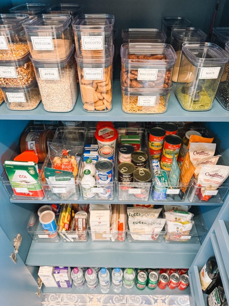 Despensa azul com potes transparentes com etiquetas e bandejas com produtos setorizados