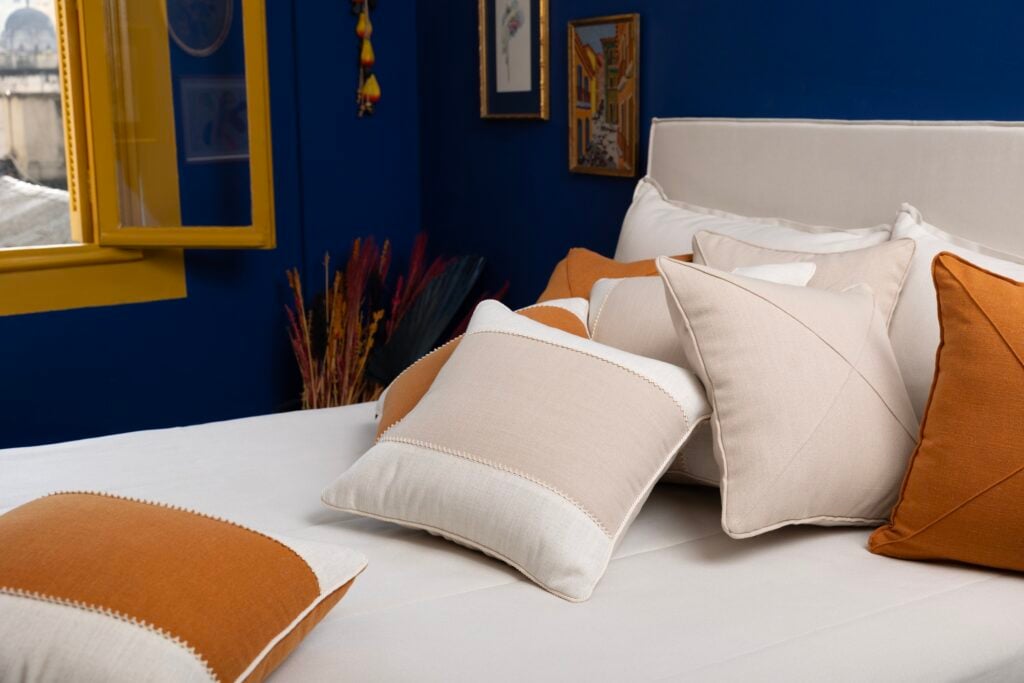 Cama com almofadas variadas em tons claros e caramelo