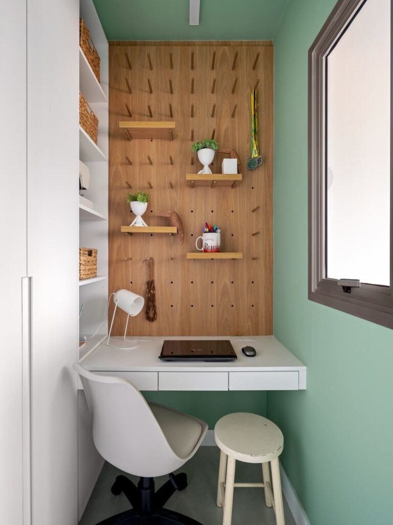Pequeno escritório em casa, com pegboard, vasinhos com plantas, bancada suspensa branca