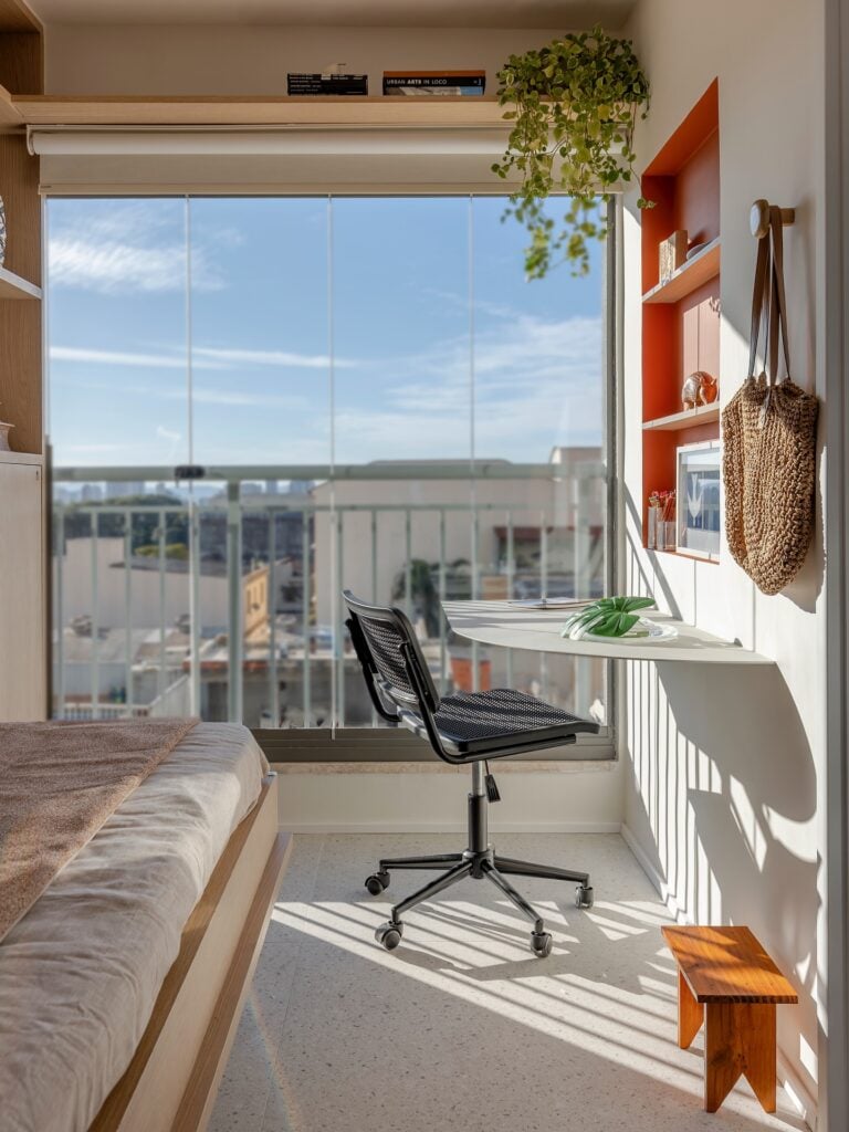 Escritório em casa com iluminação natural, bancada suspensa e cadeira preta