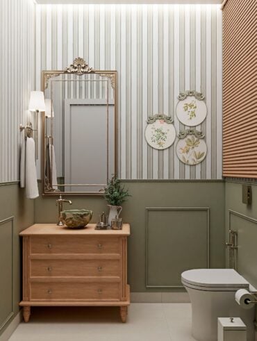 Lavabo pequeno com meia parede verde com boiserie, papel de parede listrado, bancada de madeira com gavetas e cuba de apoio