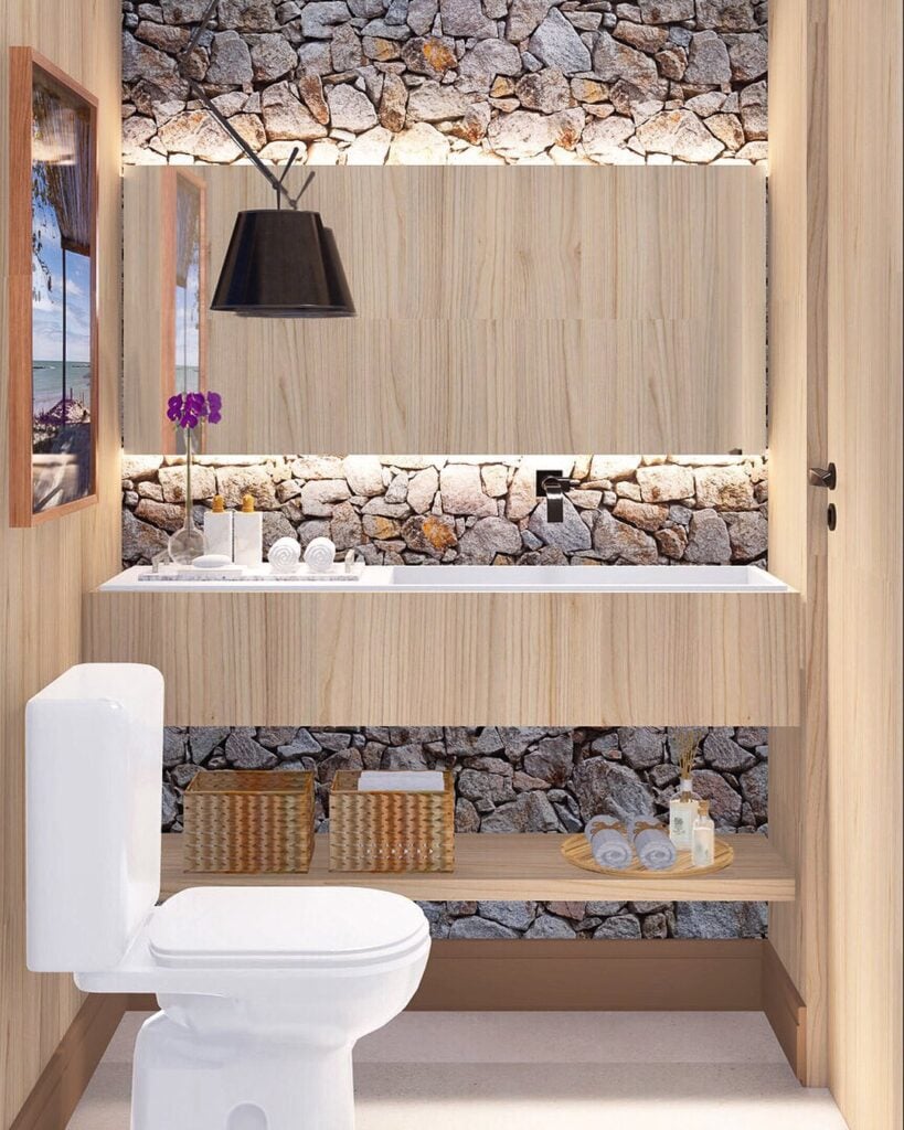 Lavabo pequeno com parede de pedras, bancada suspensa com cuba embutida e bandeja decorativa