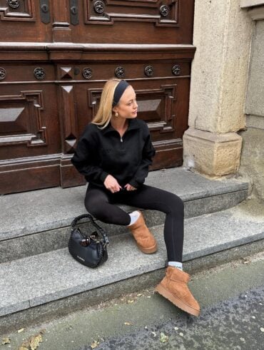 Mulher jovem e magra com pele clara. Ela usa moletom, legging, faixa no cabelo e botas ugg