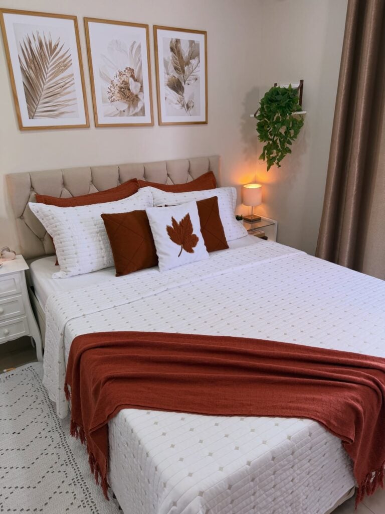 Quarto com cabeceira capitonê e cama posta em branco e tons terrosos