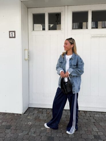 Mulher jovem e magra de pele clara. Ela usa jaqueta jeans com calça esportiva.