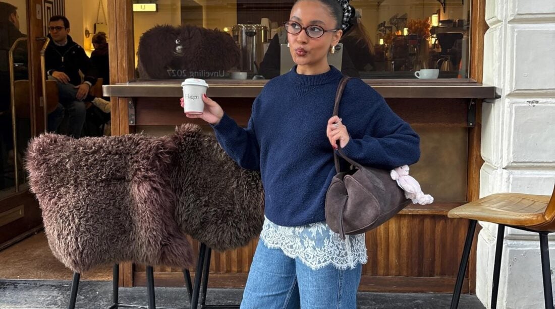 Mulher jovem com look com suéter, saia de renda mini, calça jeans e bota